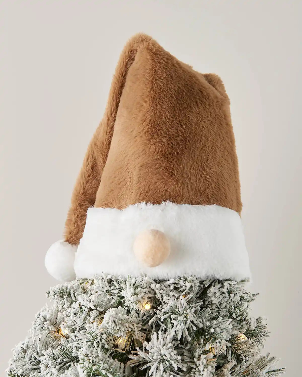 Decorative gonk brown Santa hat on a Christmas tree with a plain background