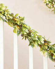Decorative green garland with mistletoe and pinecones on a staircase banister on neutral background