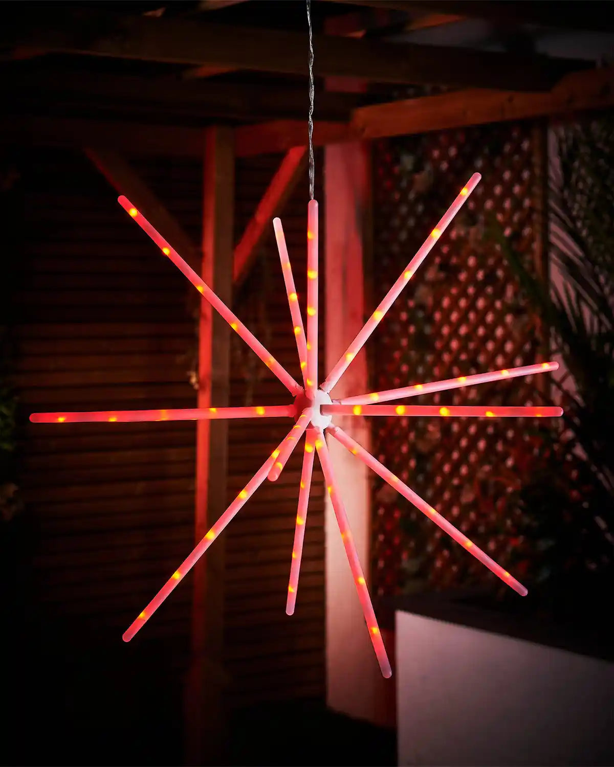 Decorative light fixture shaped like a star with red and white lights against a dark background.
