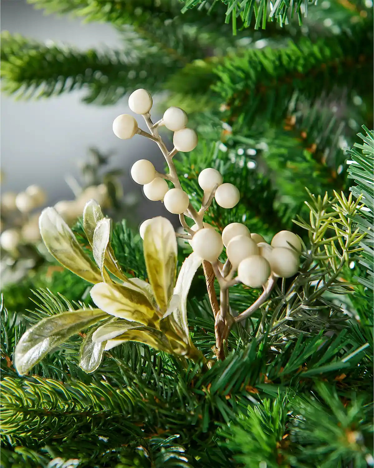 Decorative mistletoe branch with white berries on a green Christmas tree.