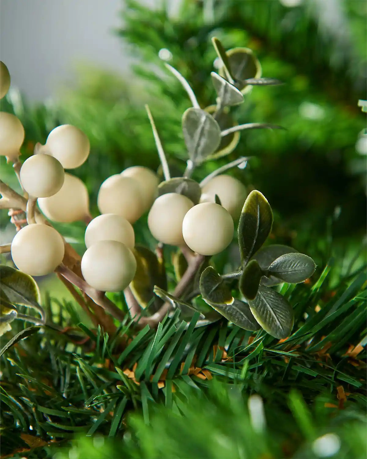 Decorative mistletoe with greenery and white berries on a blurred green background