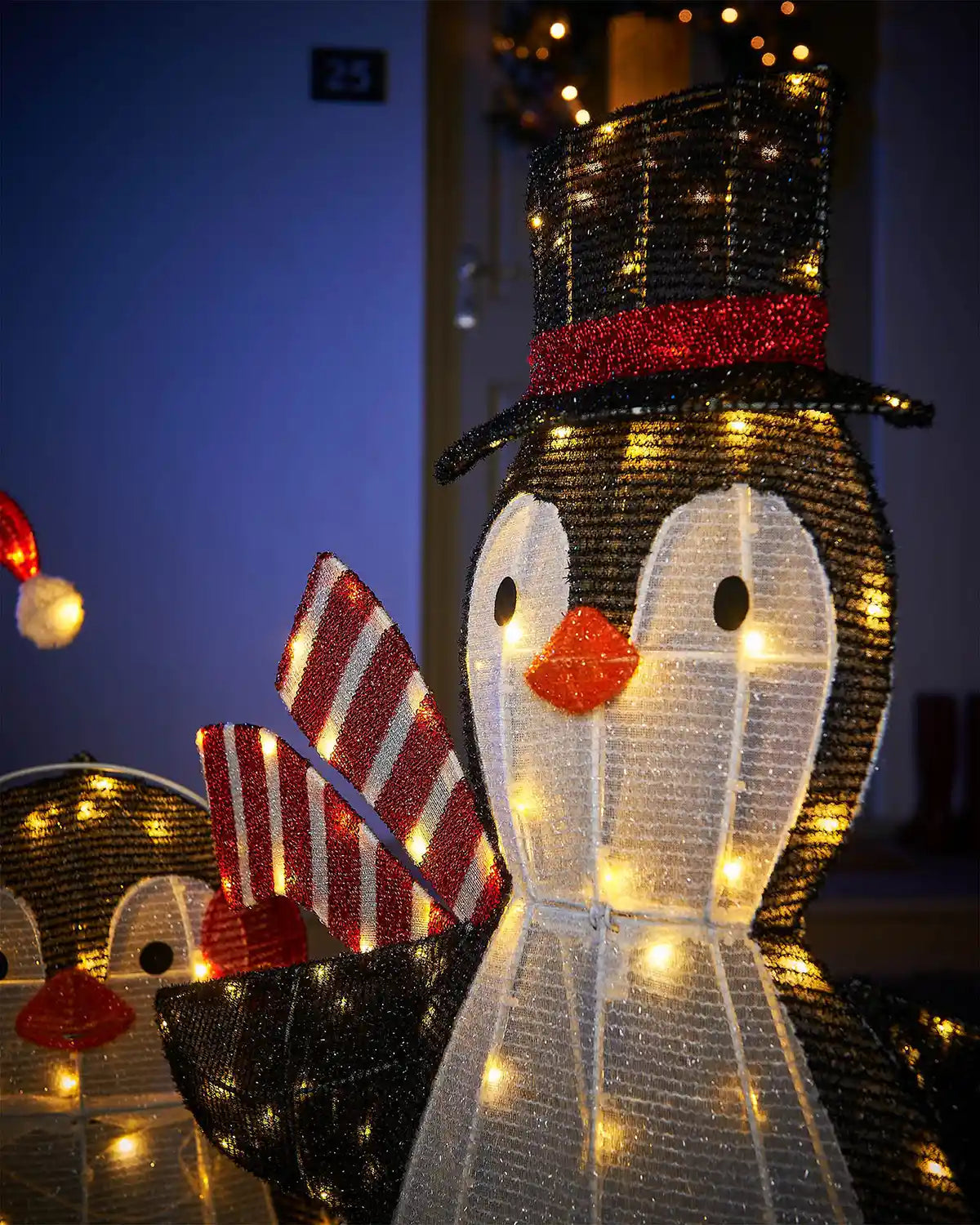 Decorative penguin lights with a festive hat and scarf on a dark background