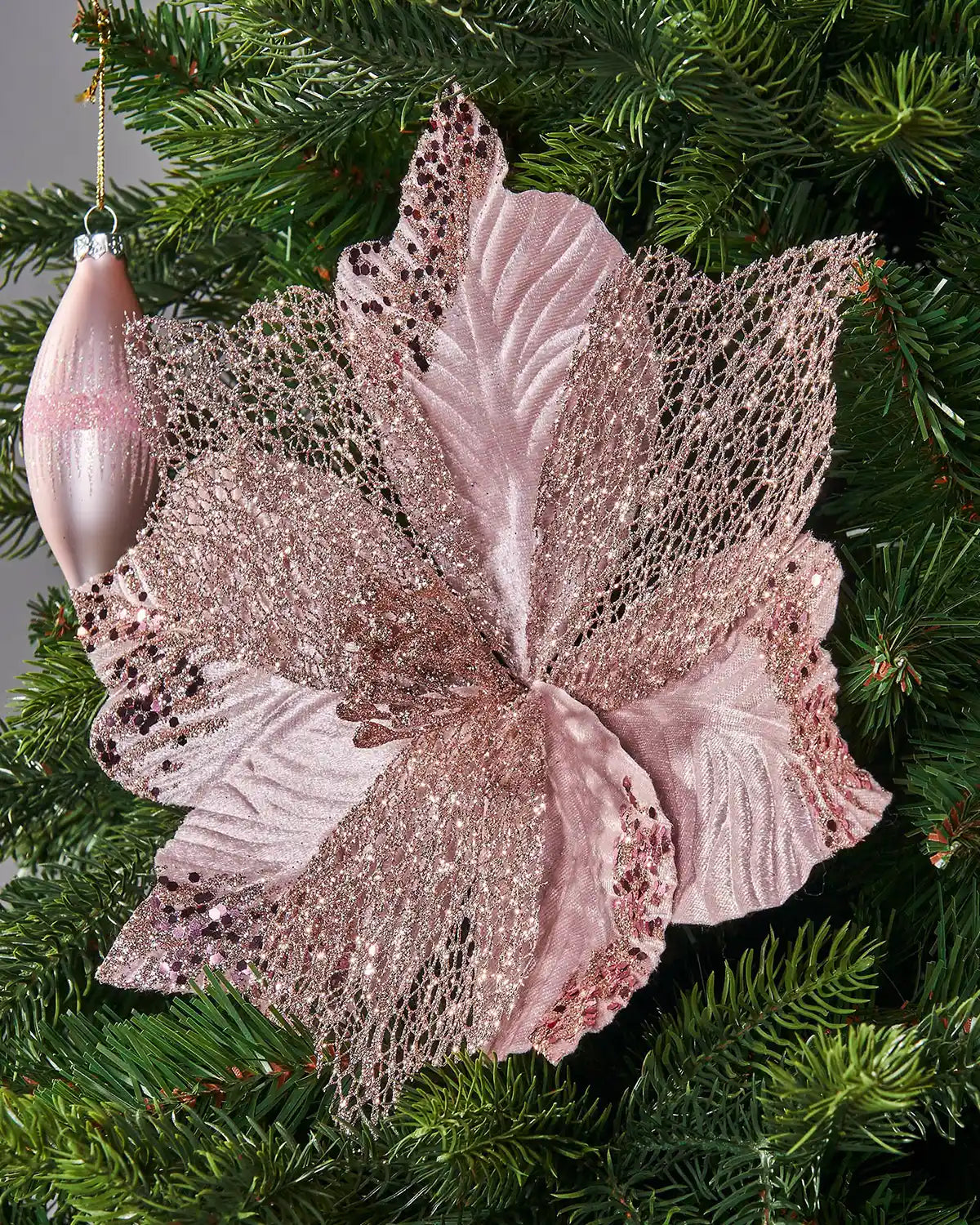 Decorative pink flower Poinsettia
 with a stem on a Green Christmas tree and pink baubles