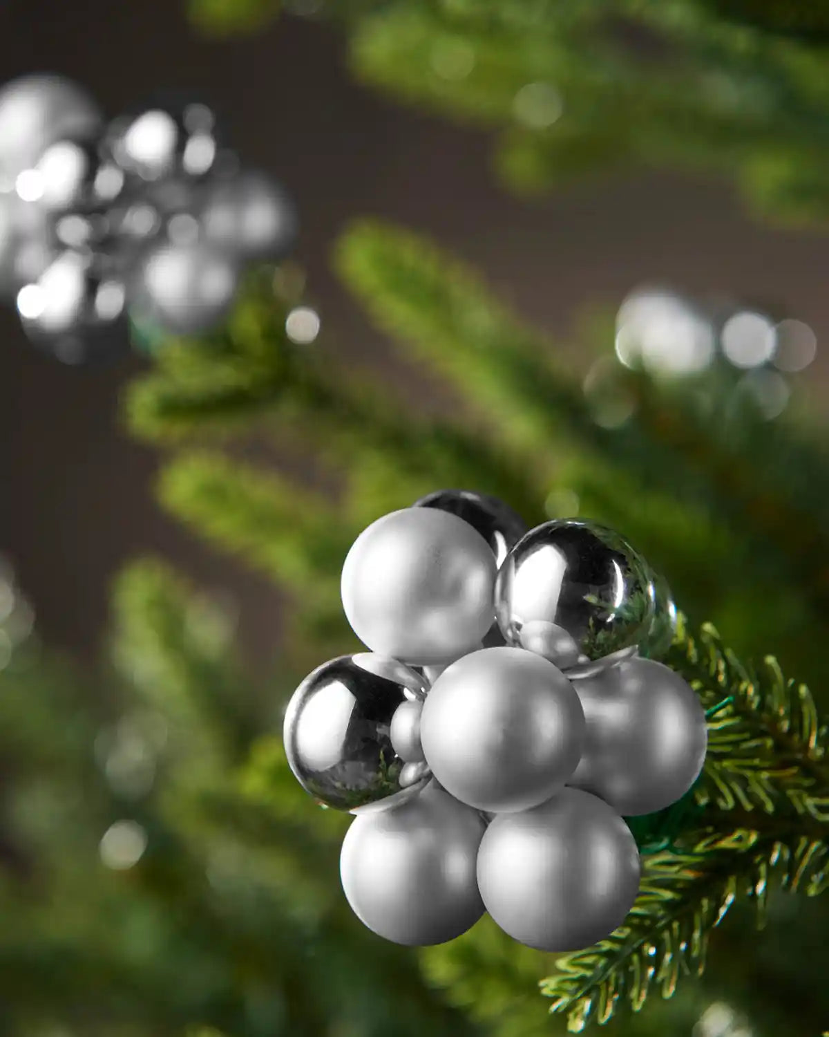 Decorative silver and white spherical ornament on a branch with a blurred background