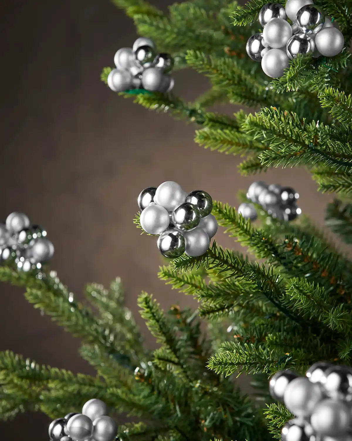 Decorative silver berries on a Christmas tree against a neutral background