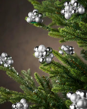 Decorative silver berries on a Christmas tree against a neutral background
