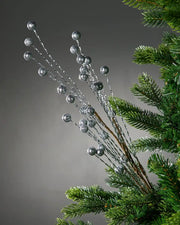 Decorative Christmas tree pick with silver berries on a Grey background on a green Christmas tree
