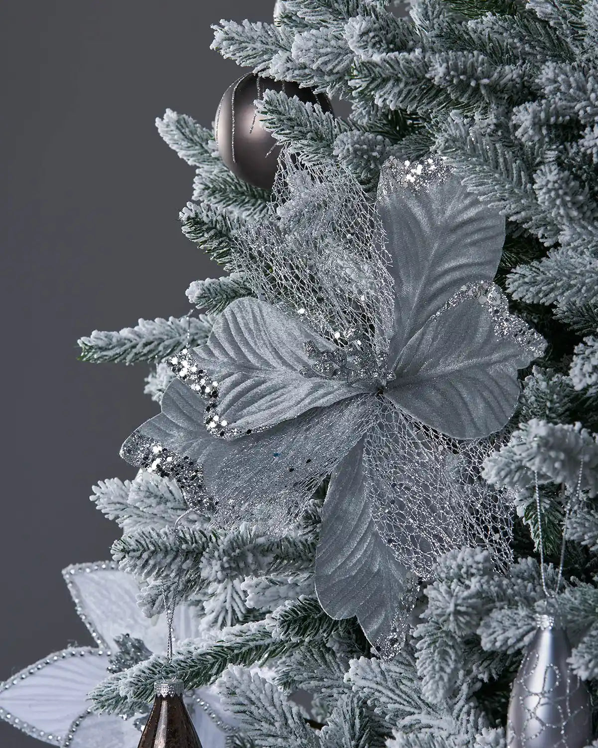 Decorative silver poinsettia on a Christmas tree with a dark background