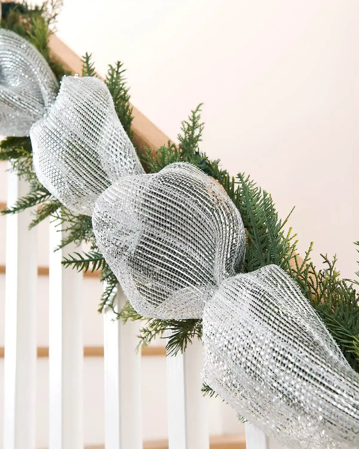 Decorative transparent silver mesh ribbon on a Christmas garland on a staircase banister with a neutral background