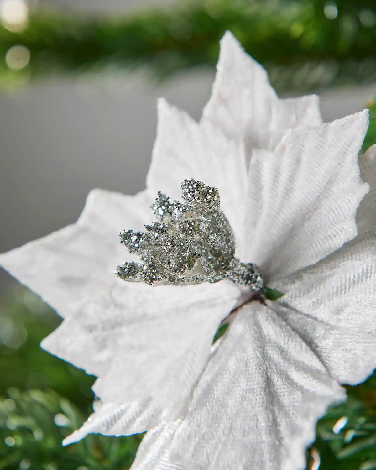 Close up of a Decorative white flower with a silver glitter middle against a blurred green background