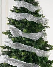Decorative white mesh ribbon on a Christmas tree against a cream wall