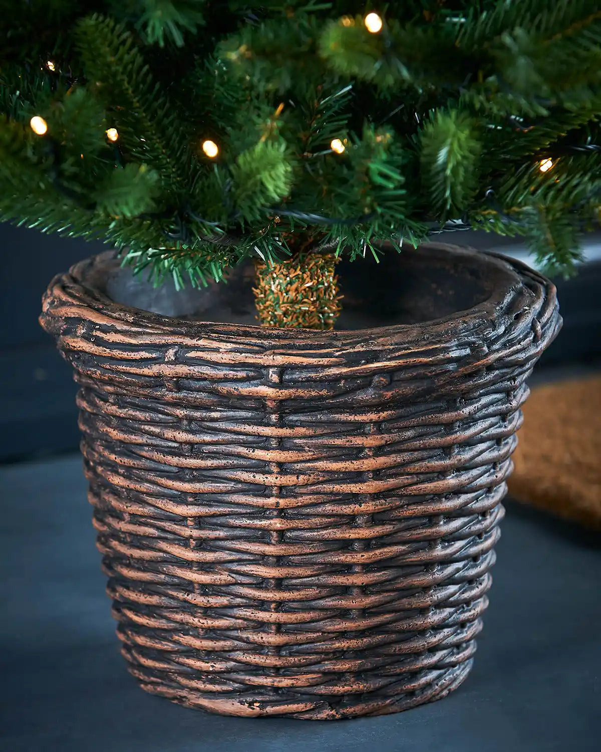 Decorative wicker basket with a small Christmas tree inside on a dark background
