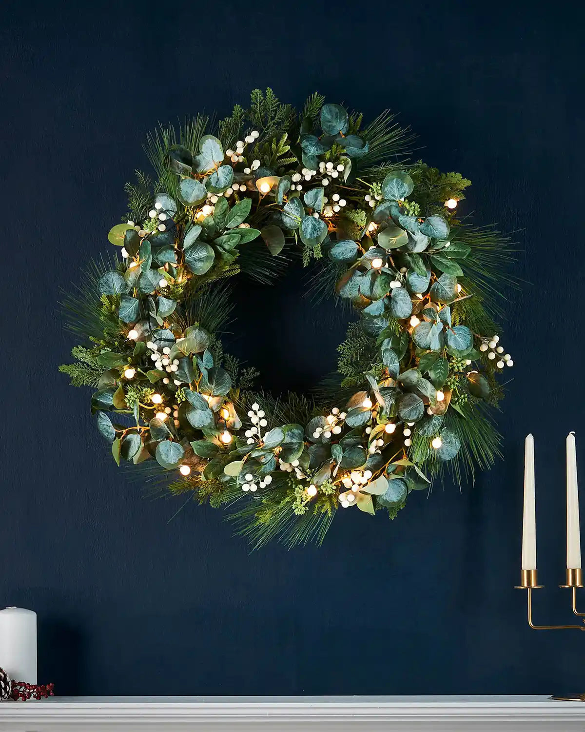 Decorative wreath with greenery, Eucalyptus and lights on a dark blue wall
