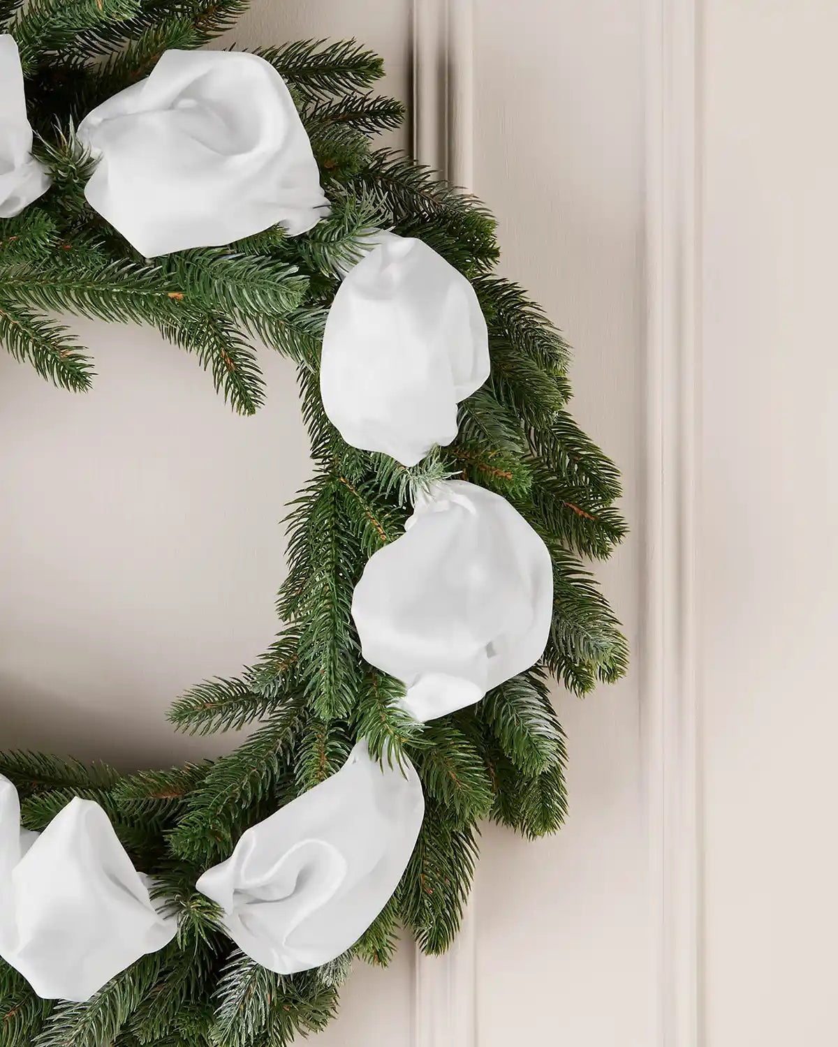 Decorative wreath with white satin ribbon on a neutral background