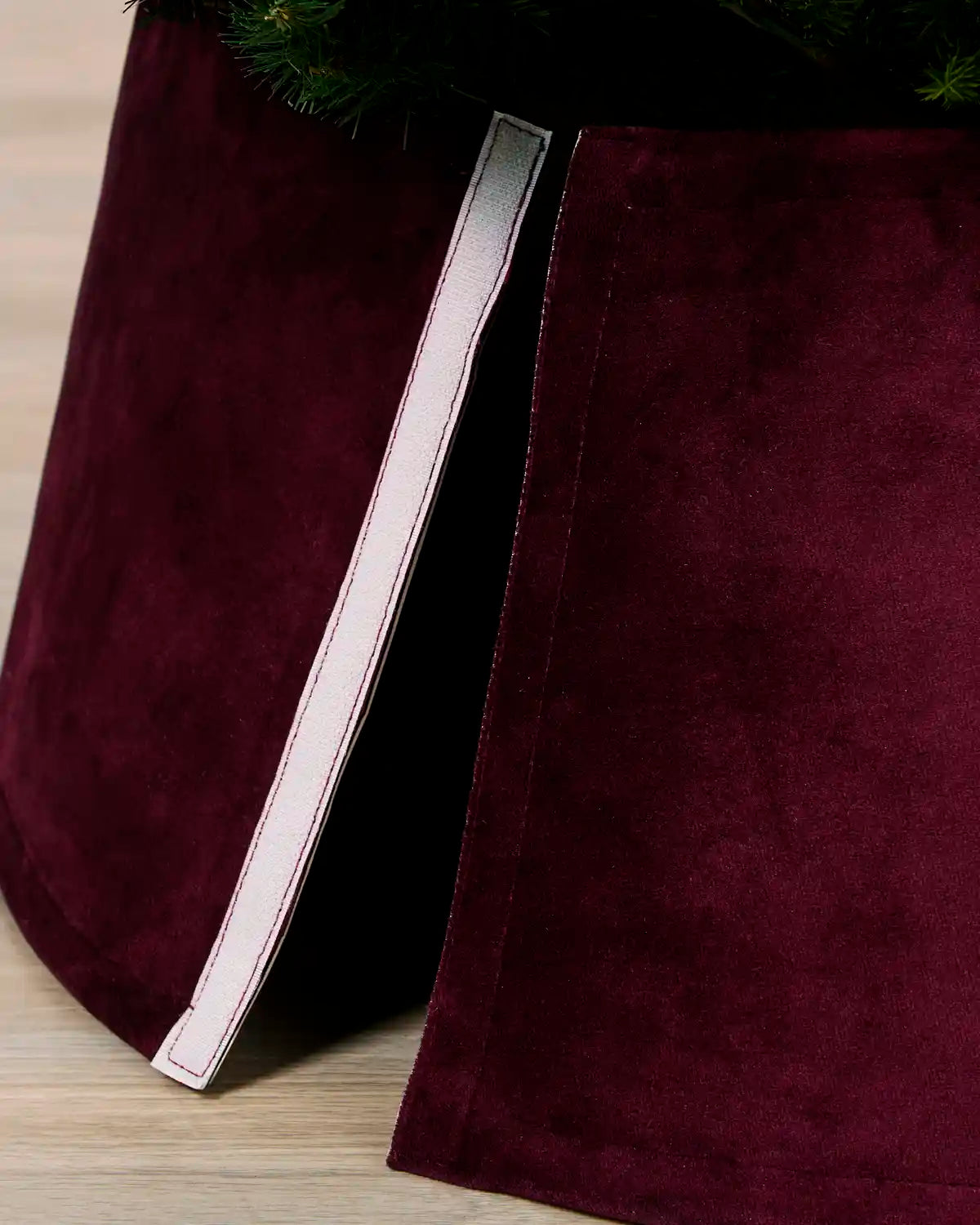 Detail of the burgundy velvet tree skirt opened at the back, showing the Velcro closure used to secure it around the tree