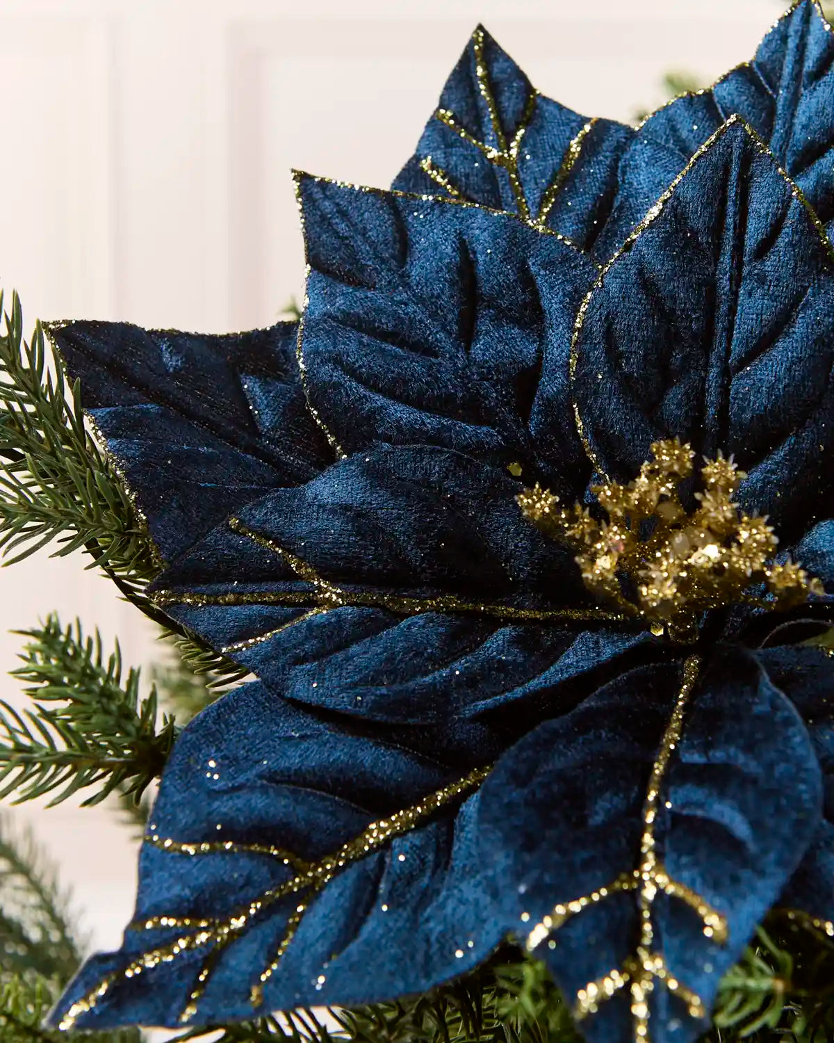 Detailed close-up of a Navy artificial poinsettia flower, showing its glittered Navy petals and sparkling gold sequin-covered center
