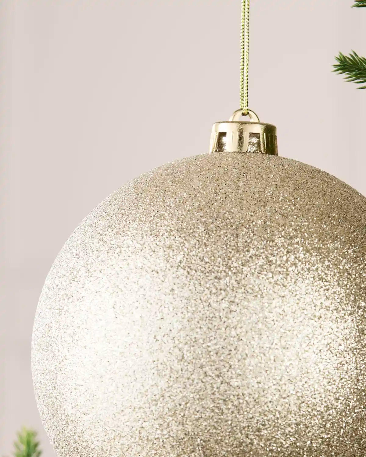 Detailed close-up of the Latte 15 cm glitter shatterproof bauble with its gold cap and matching hanging string.
