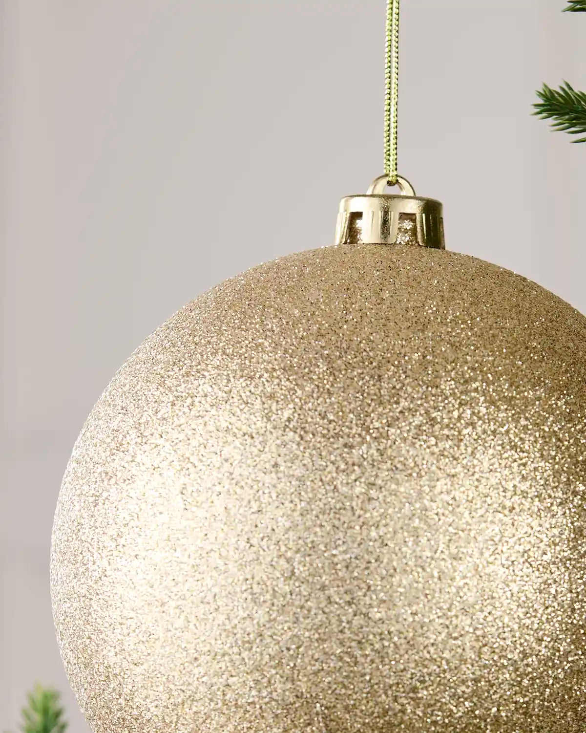 Detailed close-up of the Latte 15 cm glitter shatterproof bauble with its gold cap and matching hanging string.