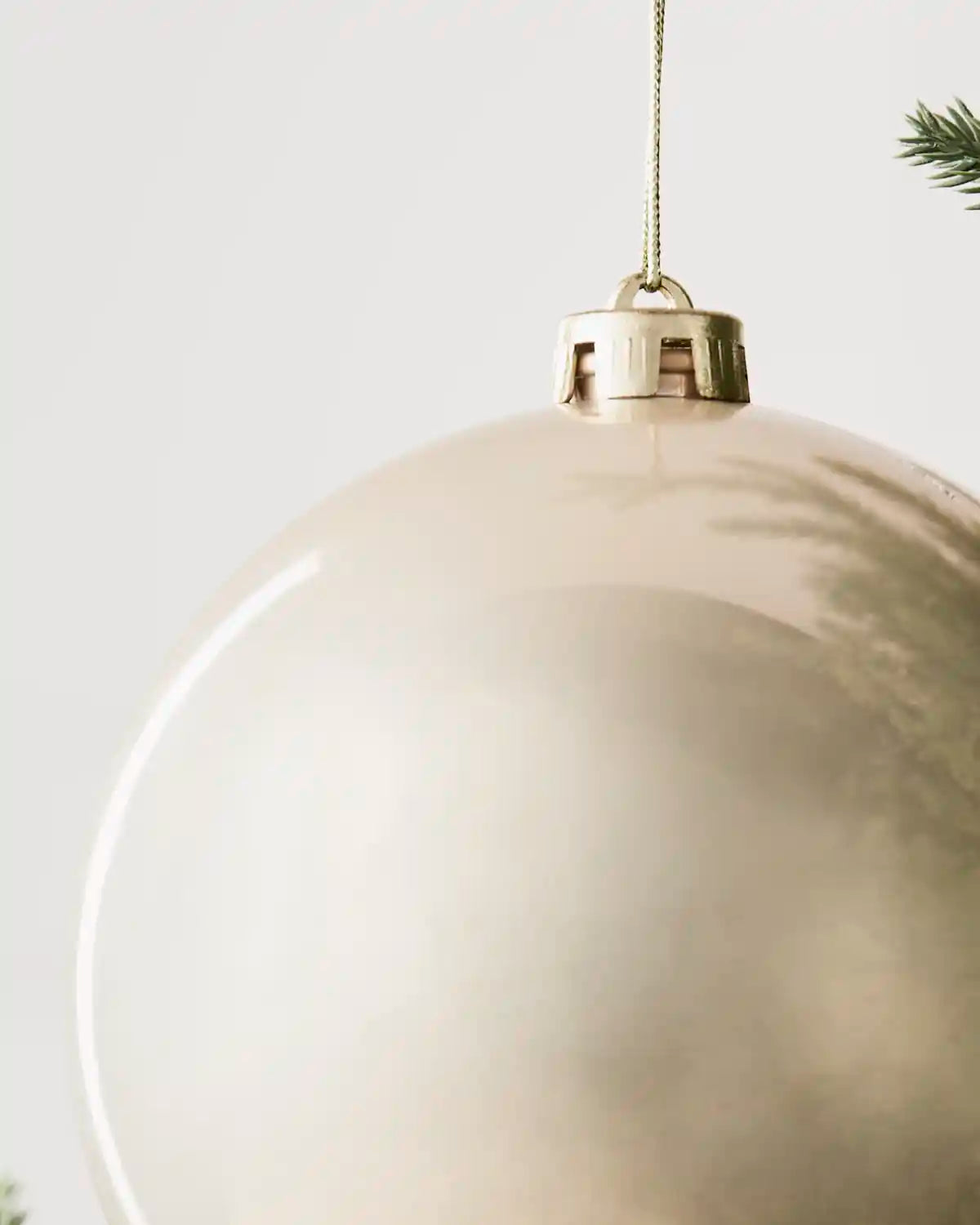 Detailed close-up of the Latte 15 cm shiny shatterproof bauble with its gold cap and matching hanging string.