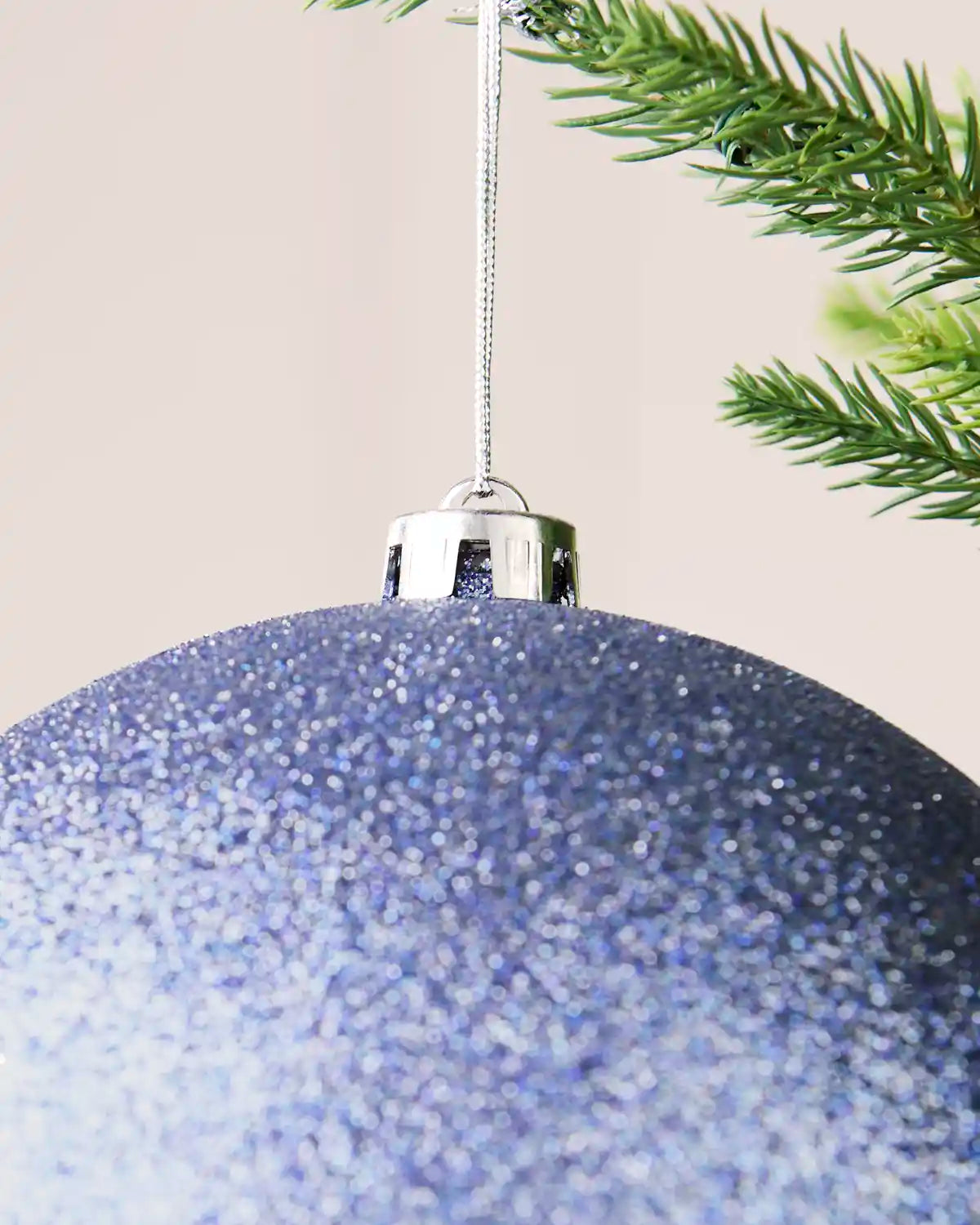 Detailed close-up of the ice blue 20 cm glitter shatterproof bauble with its silver cap and matching hanging string.