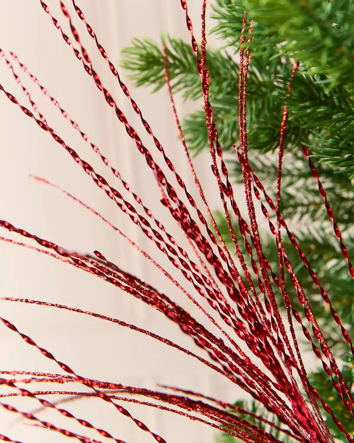 Detailed view of shimmering red twisted strands from a glitter fountain Christmas tree spray.
