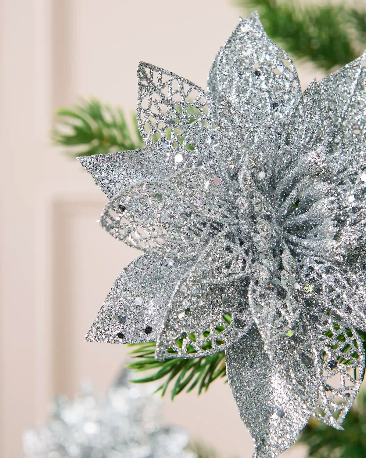 Detailed view of the Silver glitter artificial poinsettia flower, highlighting its layered petals and shimmering finish.
