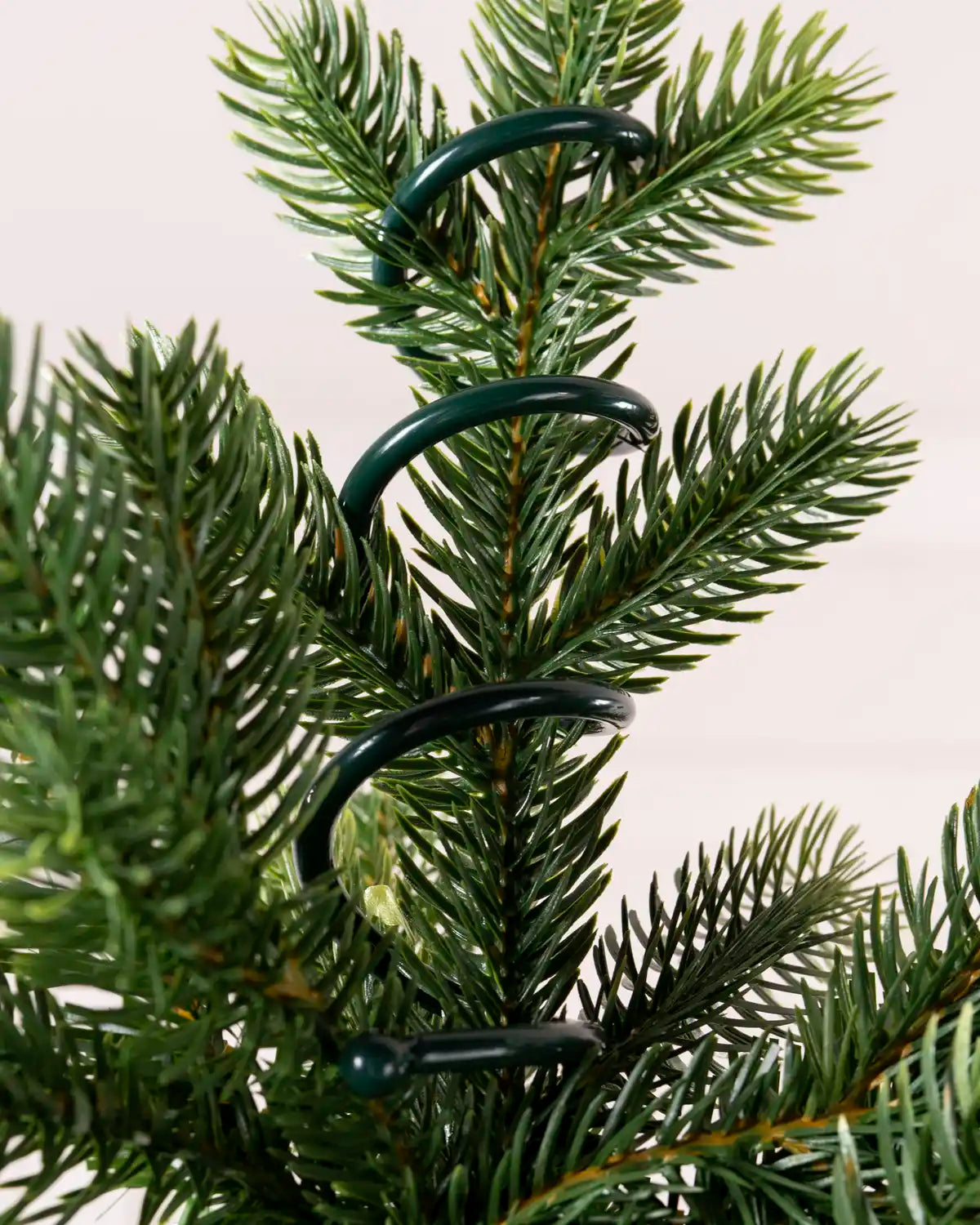 Detailed view of the green holder wrapped around the central tree branch, showing its curved support arms