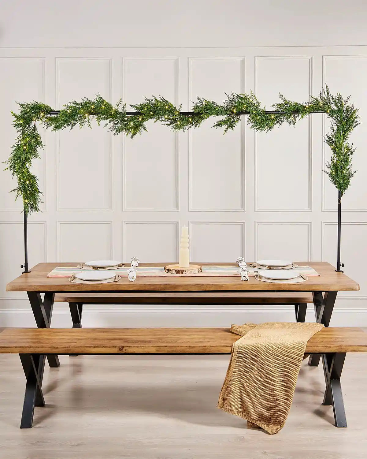 Dining table set with a garland above, against a paneled wall.