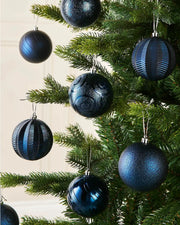 Eight Blue baubles on a Christmas tree branch against a cream wall