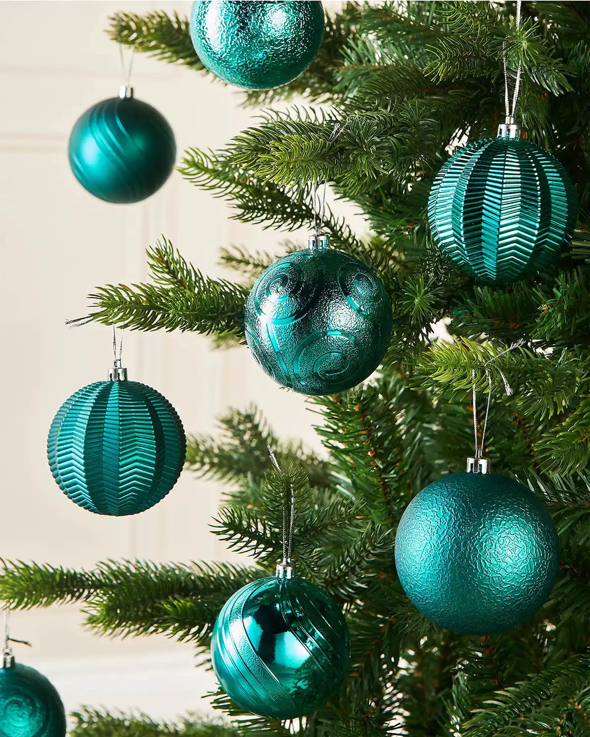 Eight Teal baubles on a Christmas tree against a cream background