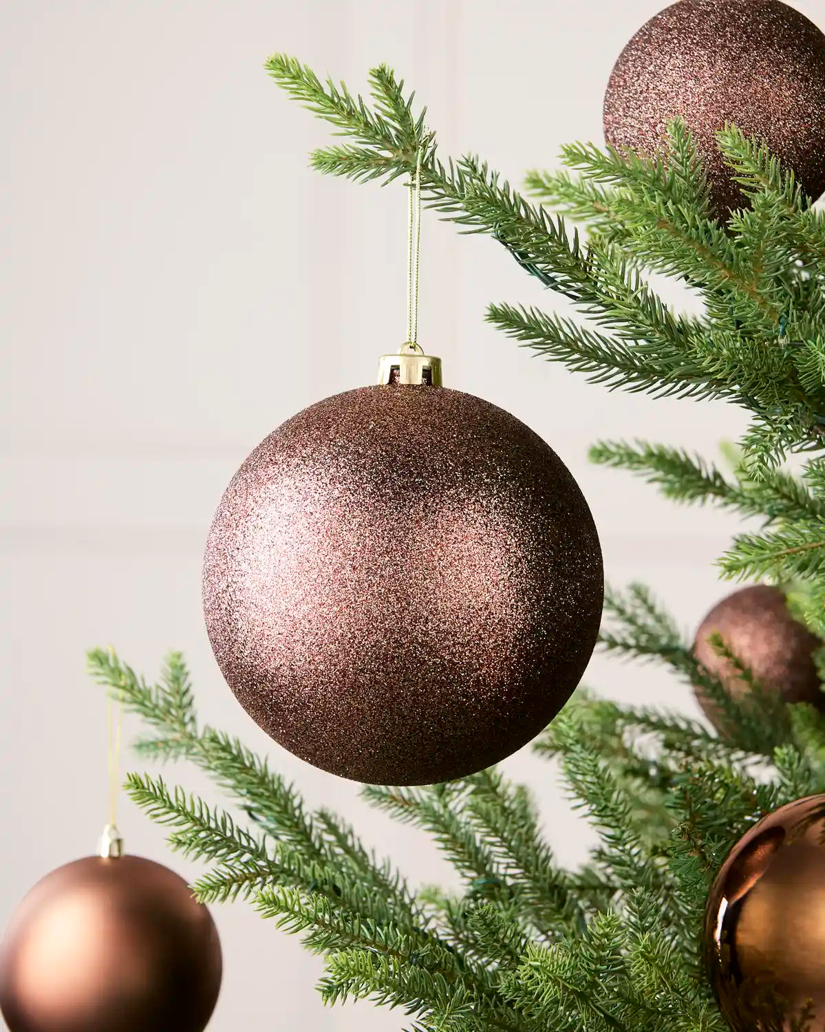 Espresso 15 cm oversized Glitter shatterproof bauble displayed on a Christmas tree with coordinating Espresso baubles.
