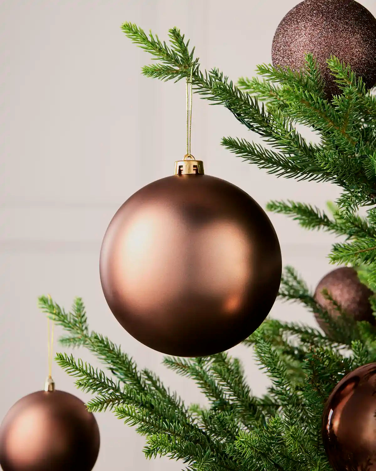 Espresso 15 cm oversized Matt shatterproof bauble displayed on a Christmas tree with coordinating Espresso baubles.
