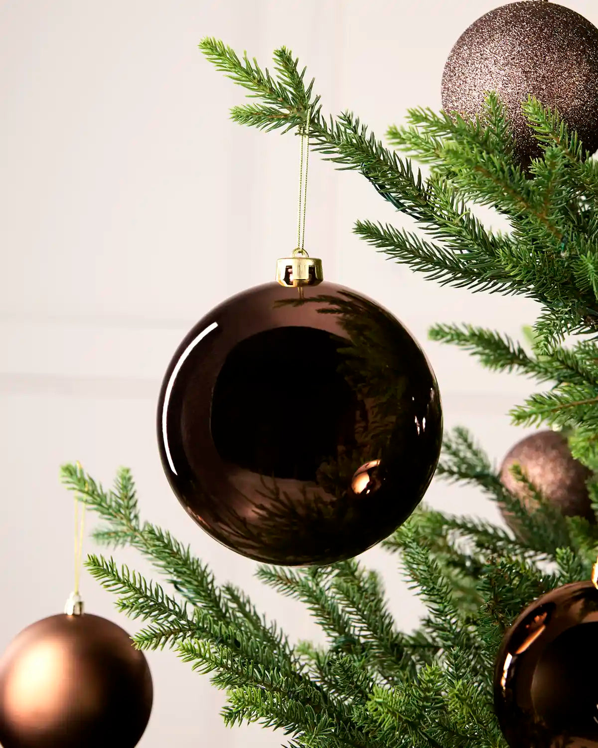 Espresso 15 cm oversized Shiny shatterproof bauble displayed on a Christmas tree with coordinating Espresso baubles.
