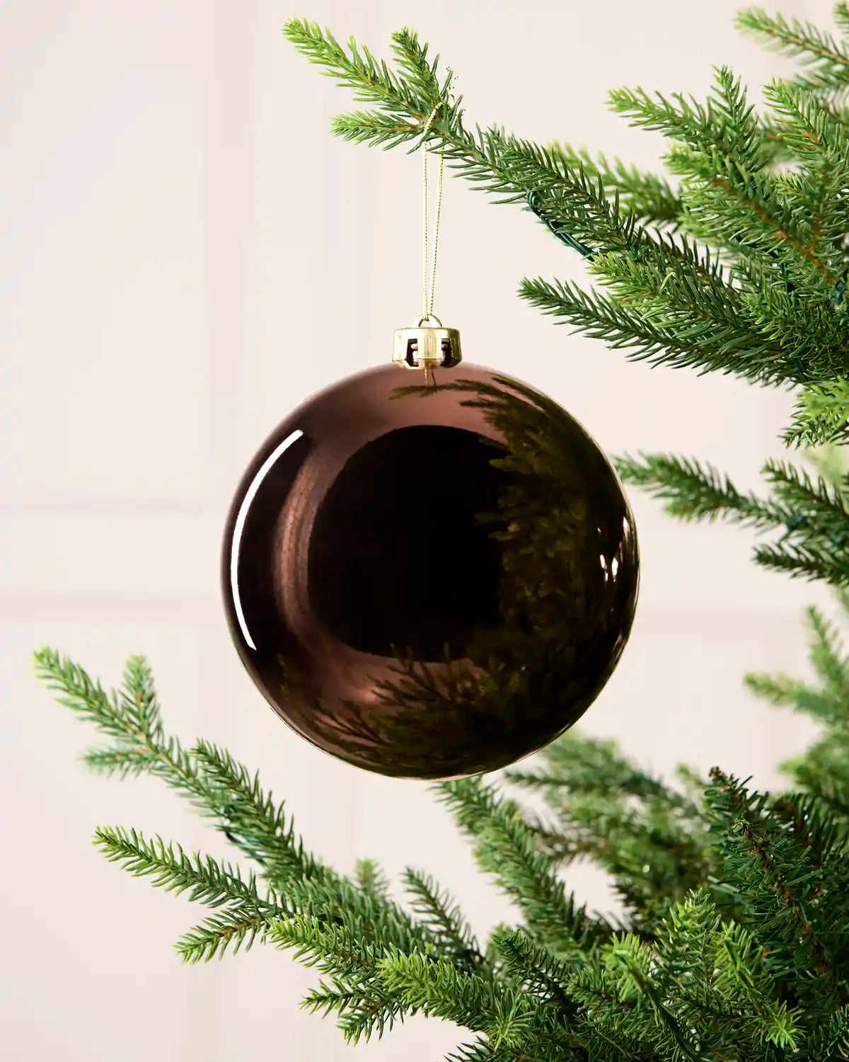 Espresso 15 cm oversized Shiny shatterproof bauble hanging on a Christmas tree with a gold cap and matching string.
