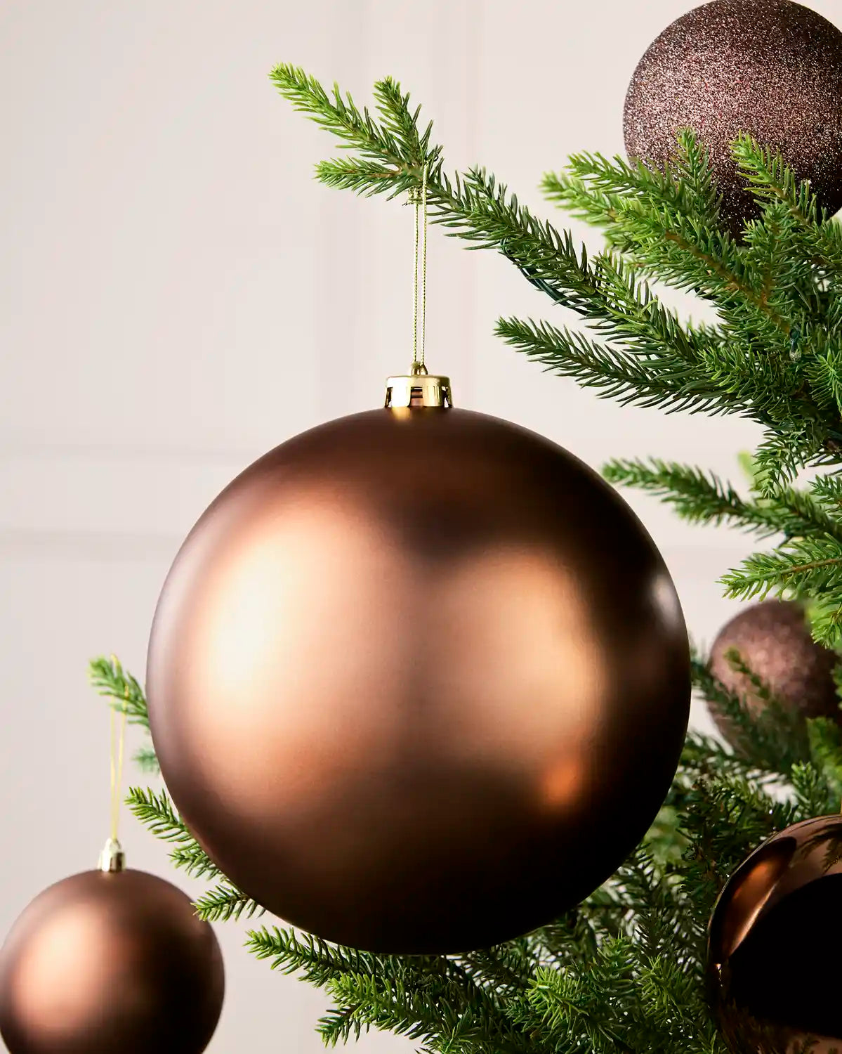 Espresso 20 cm oversized Matt shatterproof bauble displayed on a Christmas tree with coordinating Espresso baubles.
