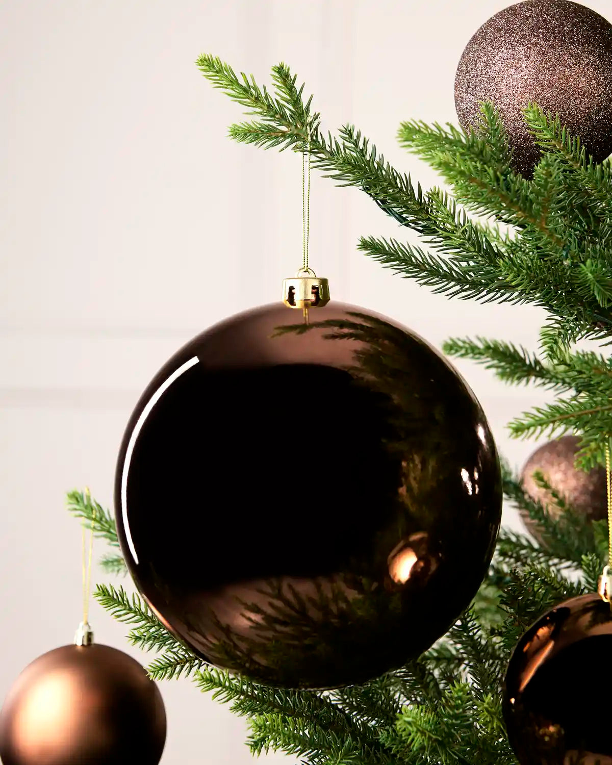 Espresso 20 cm oversized Shiny shatterproof bauble displayed on a Christmas tree with coordinating Espresso baubles.
