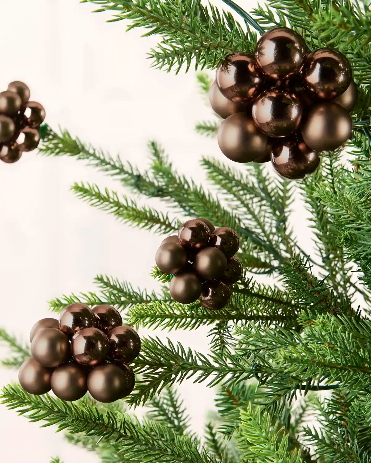 Espresso berry cluster baubles with mixed shiny and matt glass finishes displayed on Christmas branches.
