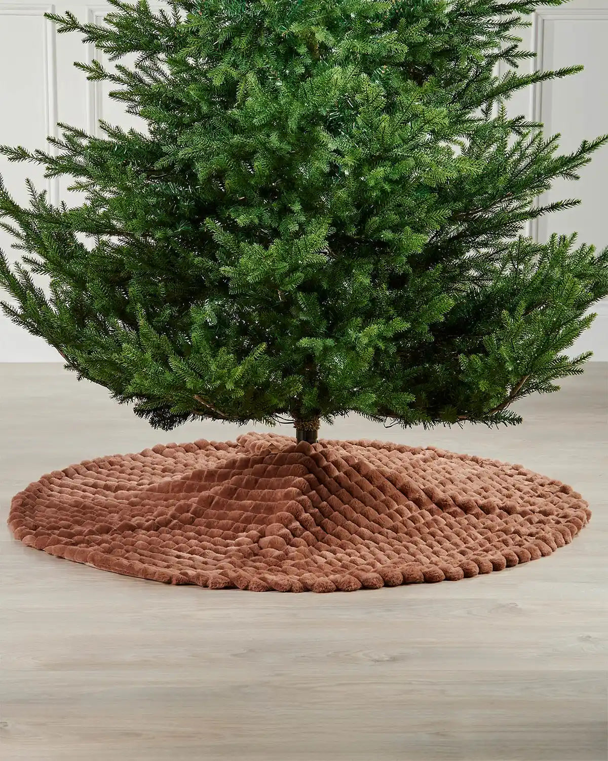 Full image of the espresso faux fur diamond tree skirt on light wooden flooring underneath green Christmas tree