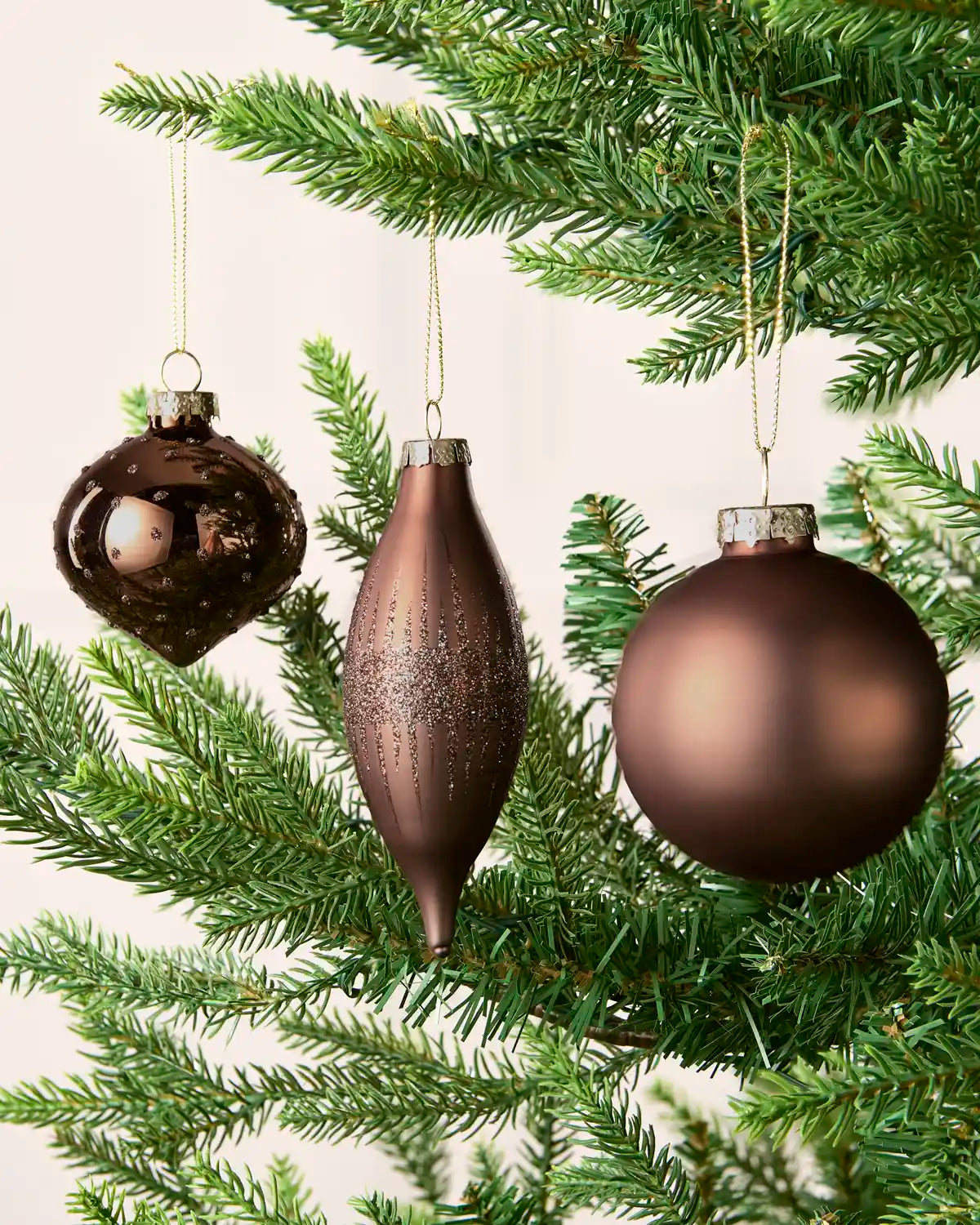 Espresso round, onion-shaped and teardrop glass baubles displayed on a Christmas tree.
