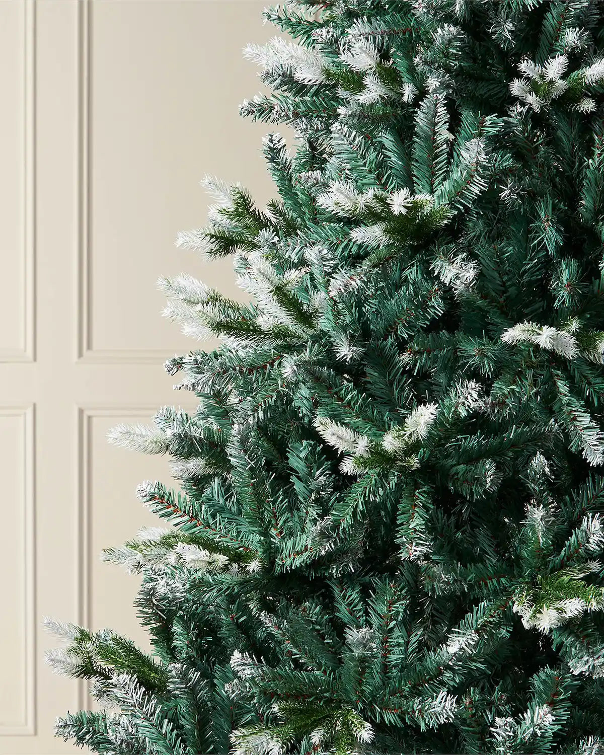 Close up of the PVC and PE tips on the Evergreen Snow Flocked Tip Christmas Tree, 6 ft on a panel textured background
