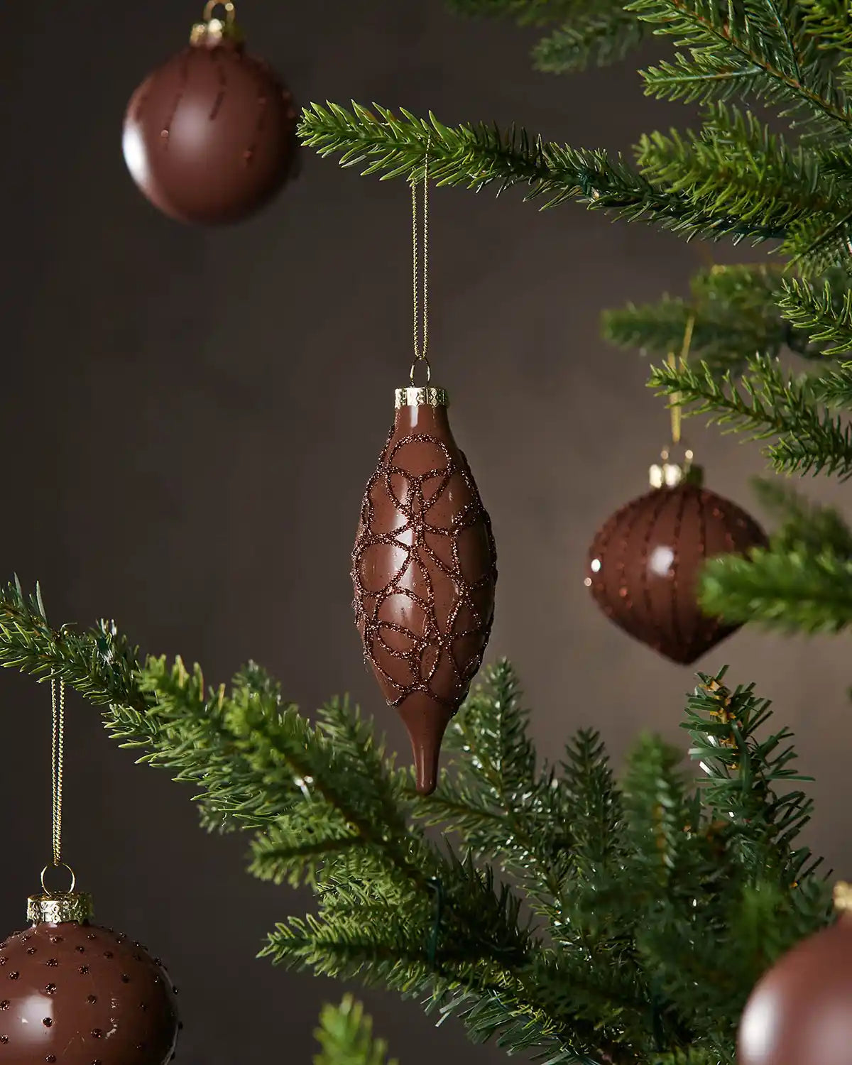Five Espresso Christmas baubles hanging on a tree with a dark background