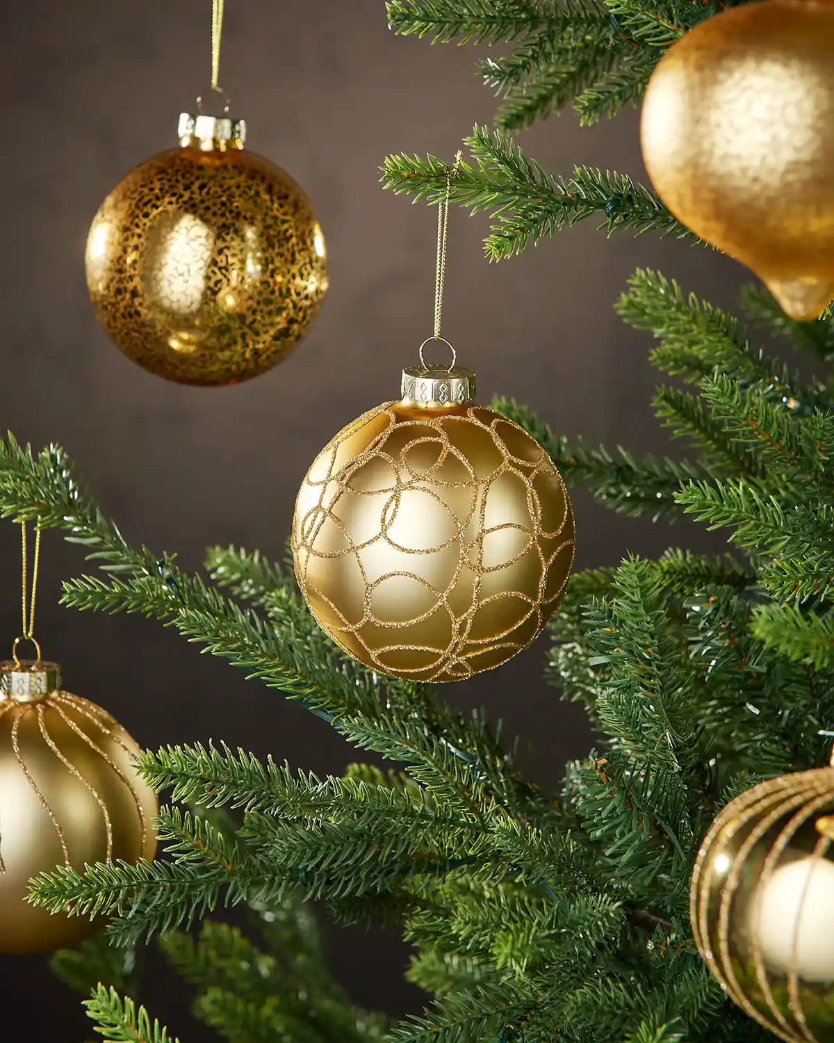 Five Gold Christmas baubles on a tree with a dark background