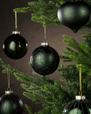 Five Sage green various shaped Christmas baubles hanging on a tree branch with a brown background
