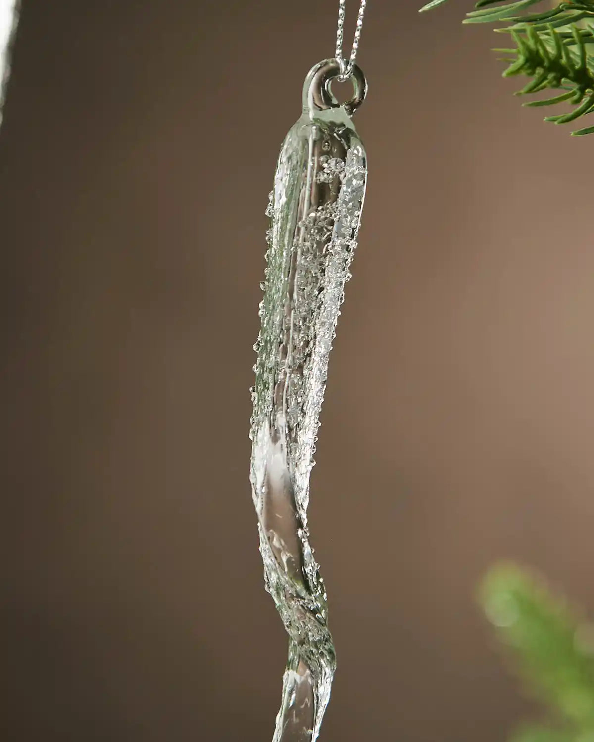 Frosted Ice crystal ornament hanging on a tree branch with a blurred background