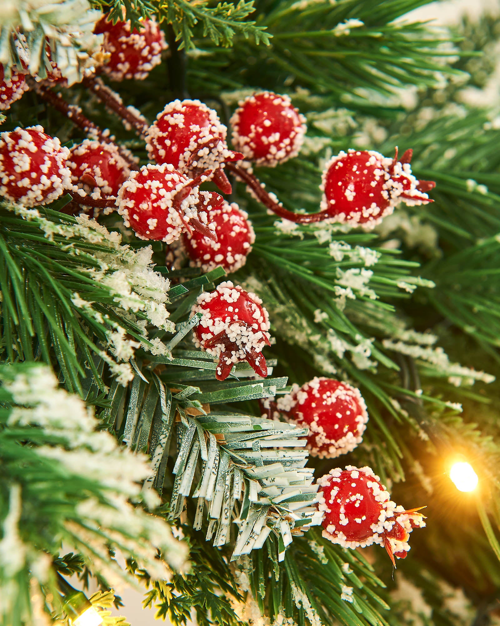 Frosted red berries on a frosted garland with a single lit bulb