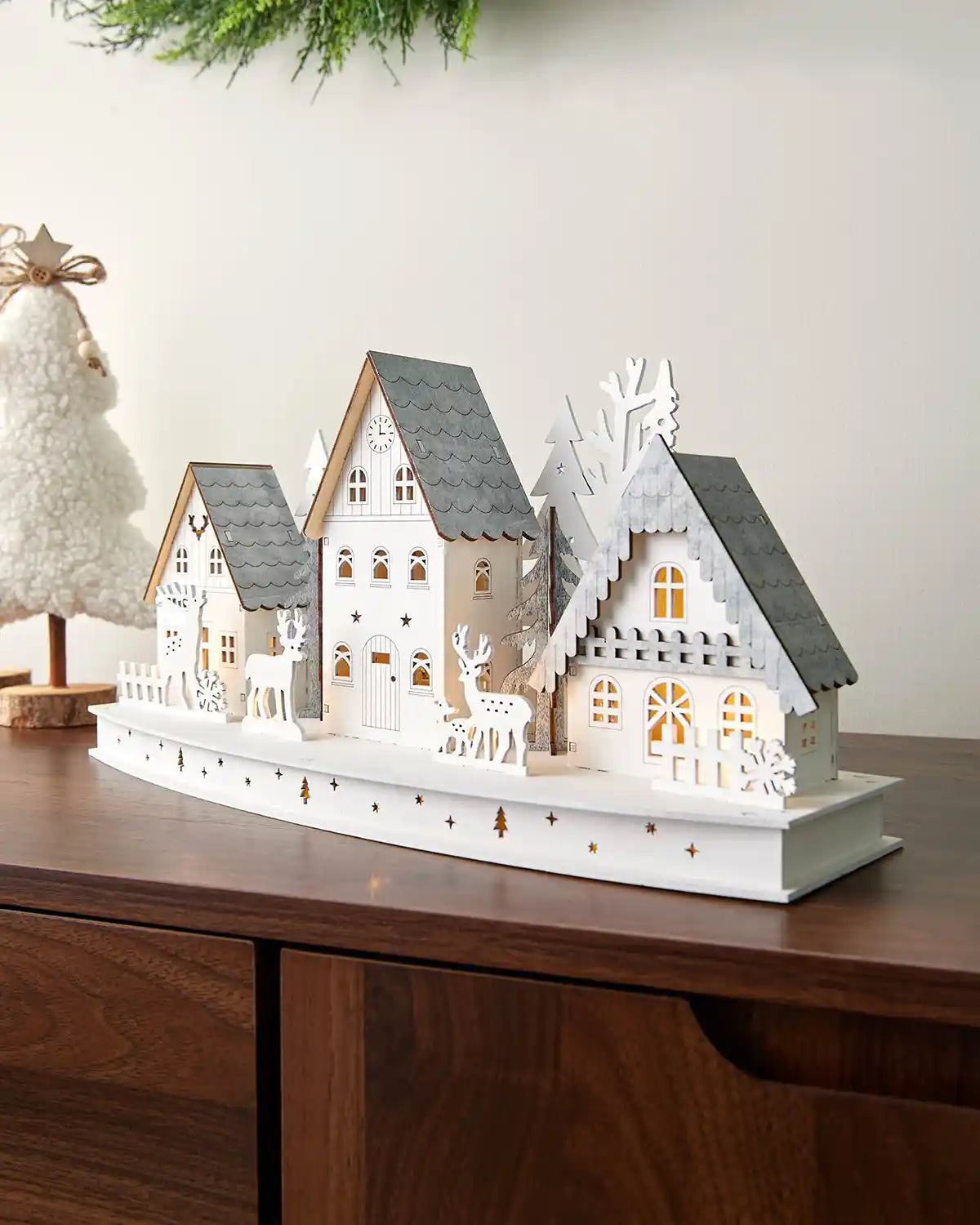 Full image of 40cm pre-lit white wooden village scene with warm white light setting on dark wood surface