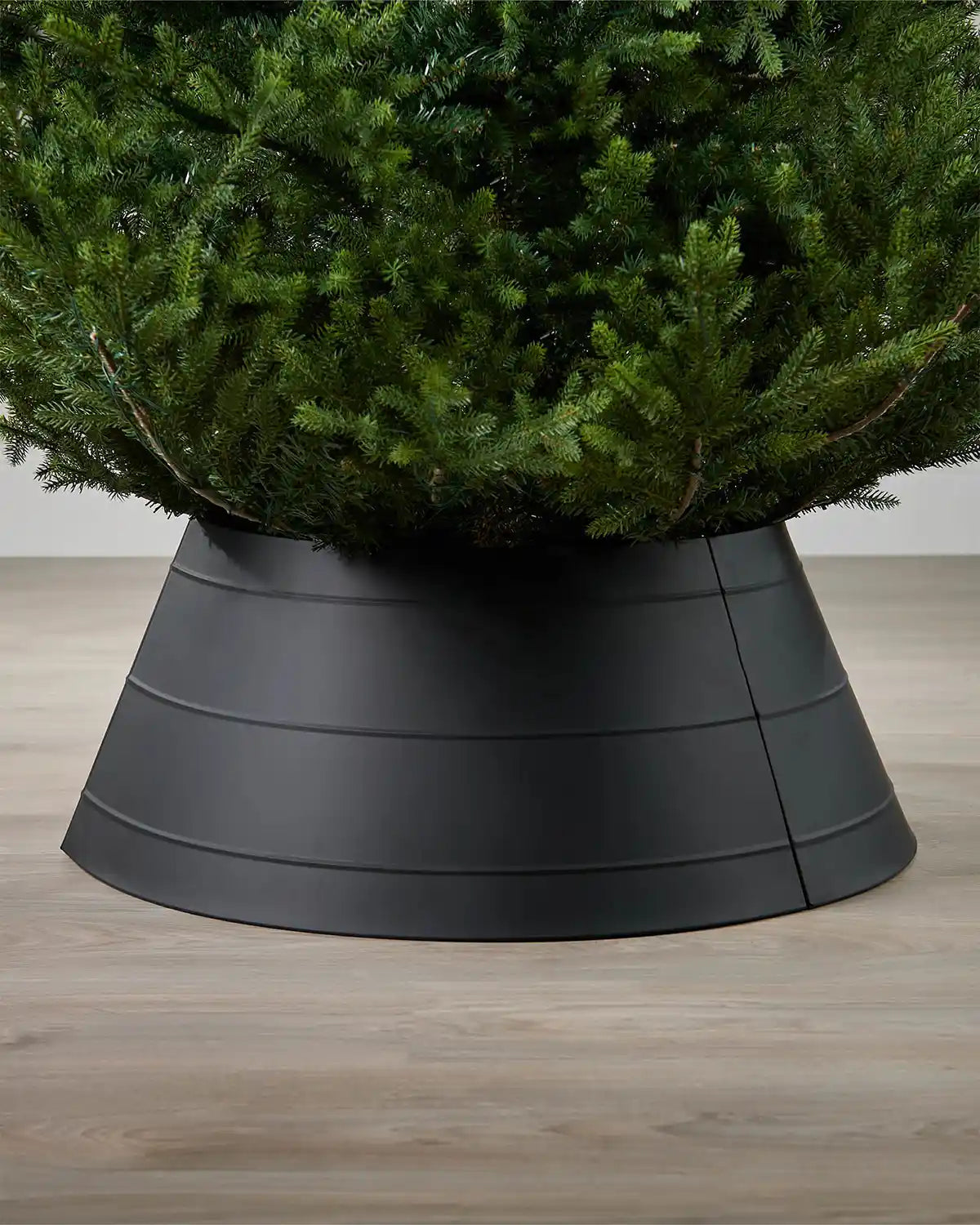 Full image of black metal tree collar on light wood flooring