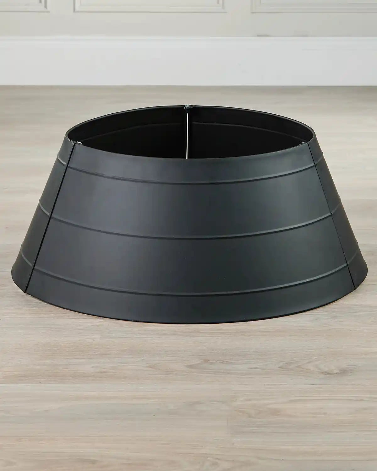 Full image of black metal tree collar without tree on light wood flooring