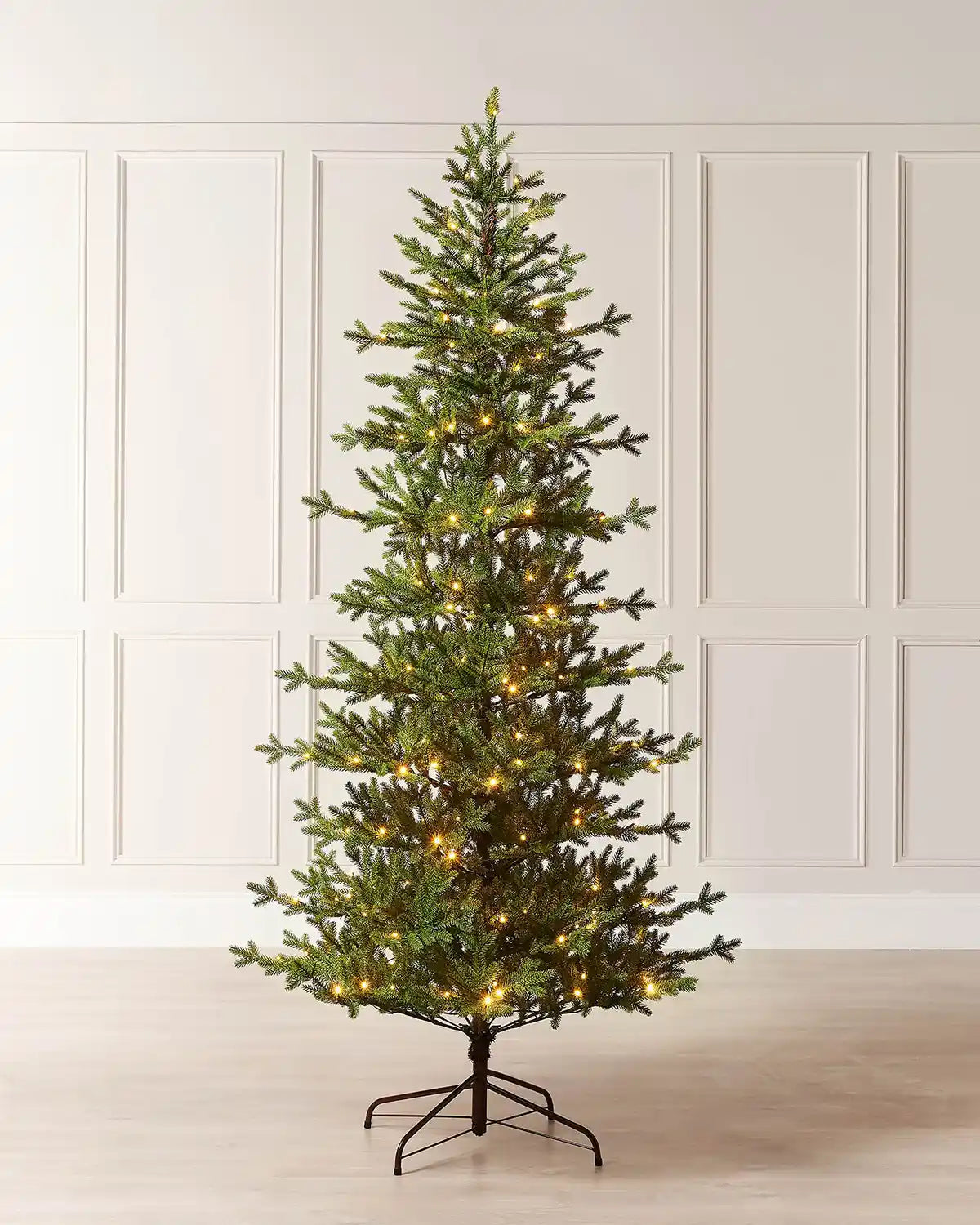 Full image of 7ft pre-lit nordic pine Christmas tree with warm white light setting in front of white panelling