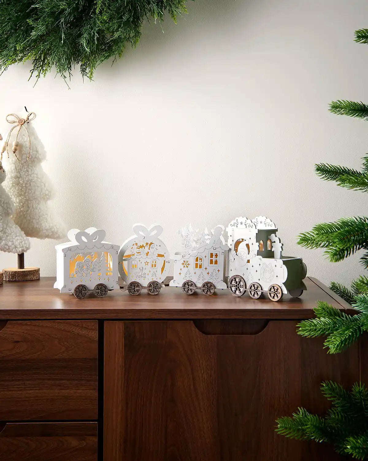 Full image of pre-lit white wooden train decoration on dark wood surface in front of white wall